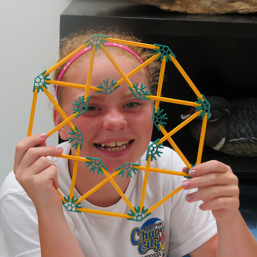 Girl smiling and holding a geometric shape she built.