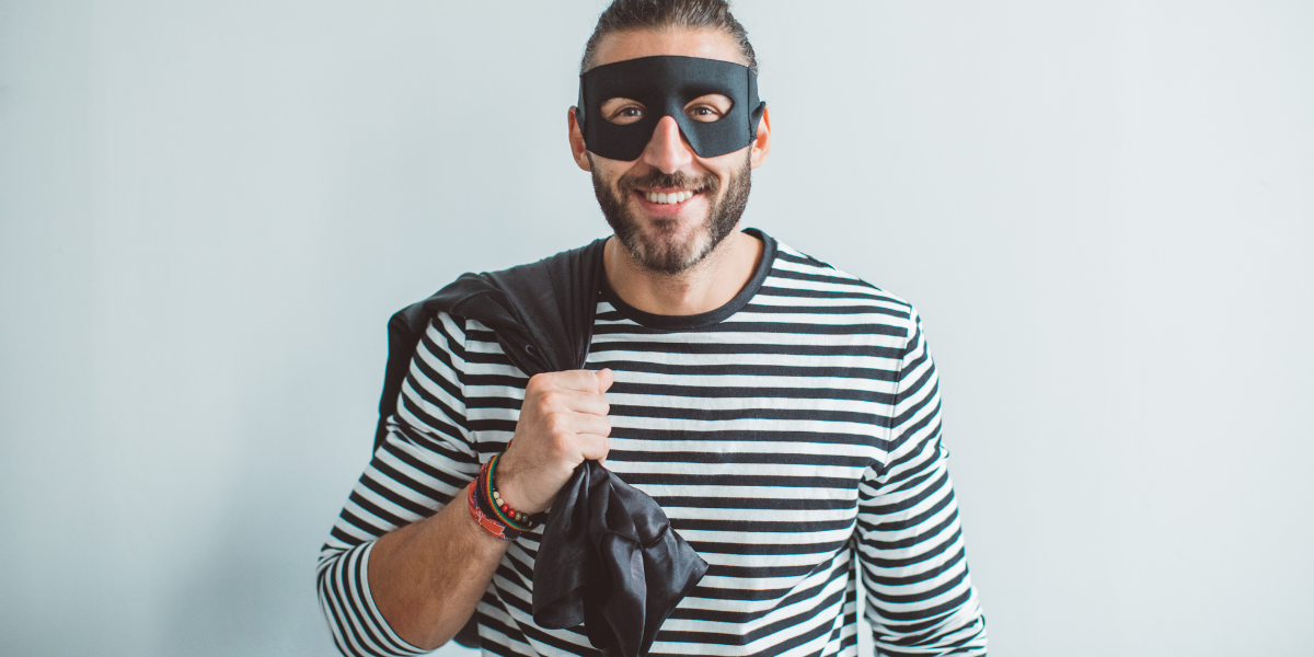 Smiling man in black mask and striped shirt holding bag, illustrating deceptive riddle scenarios about theft and assumptions