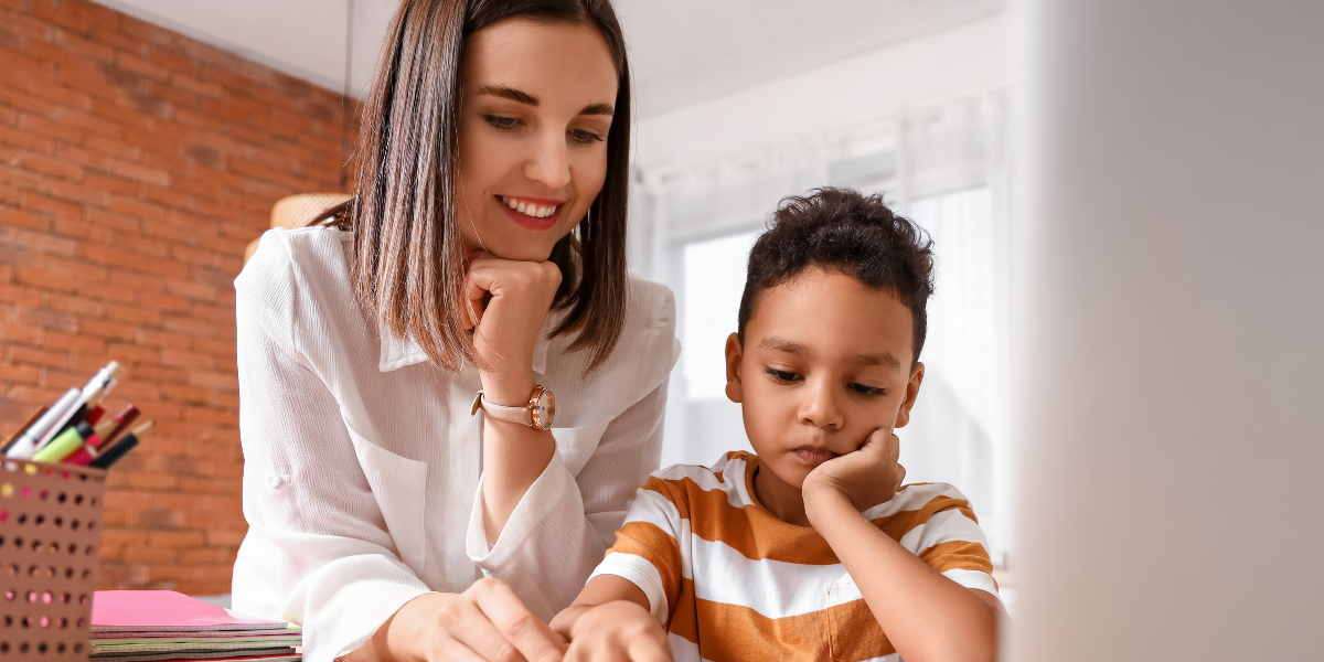 Smiling mother assists young student with schoolwork at desk, showing how parental support and one-on-one attention can help teens concentrate and develop better study habits.