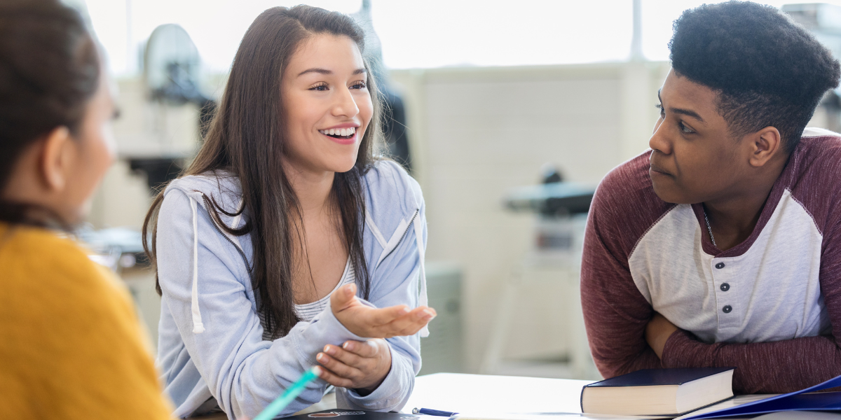 Students engaged in lively classroom debate with books and materials on desk