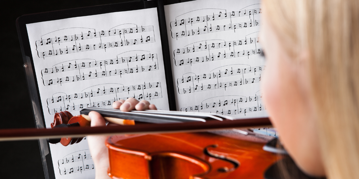 Young musician practicing violin while reading sheet music, demonstrating how beginner-friendly musical arrangements of favorite songs build confidence and keep practice exciting. Sheet music for kids' favorite movies and games makes learning instruments more engaging and educational.