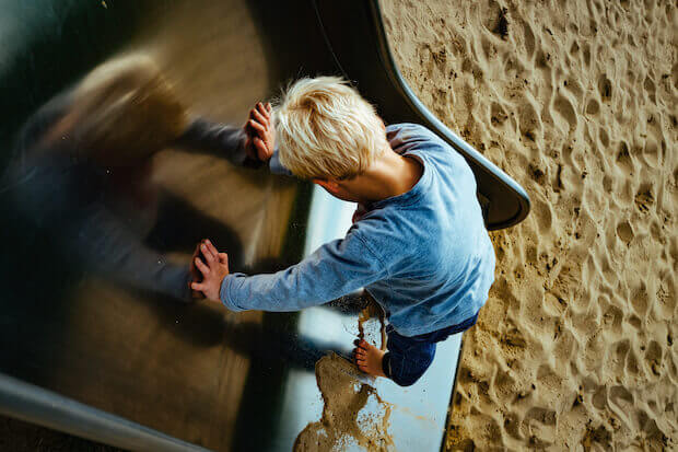 child on playground slide outside - waldorf education featured image