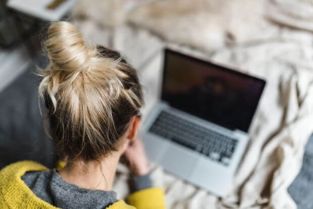 girl ponytail with laptop on bed - recognize autism signs in teens article featured image