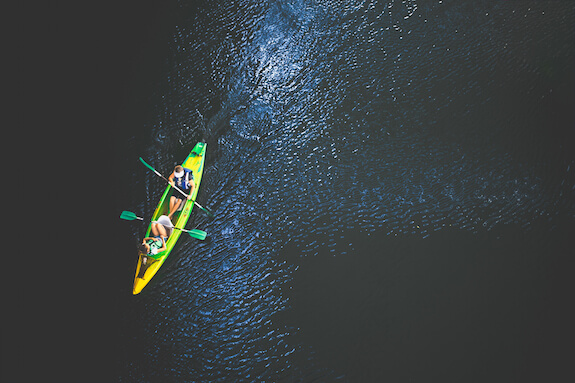 life lessons to teach kids when kayaking - blog post featured image of two people in a kayak