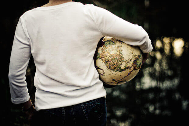holding a globe - featured image for article on how to raise bilingual kids