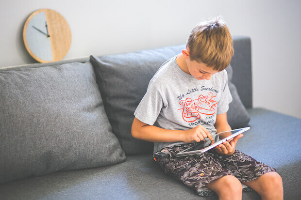teaching students with iTunes U featured image of boy using tablet on couch